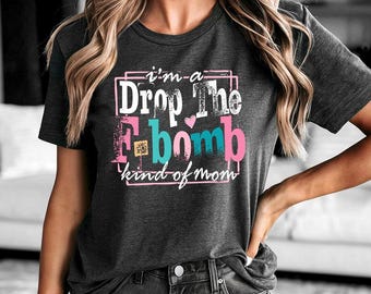 May include: Dark gray t-shirt with the text "I'm a Drop The F-bomb kind of mom" in a colorful design. The shirt has a crew neck and short sleeves. The text is in white, pink, and teal.