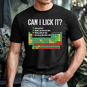May include: Black t-shirt with the text "CAN I LICK IT?" above a colorful periodic table of elements. The shirt includes a key with the phrases "Sure, go for it," "Maybe, not the best idea," "Please, don't do that," and "See you on the other side."