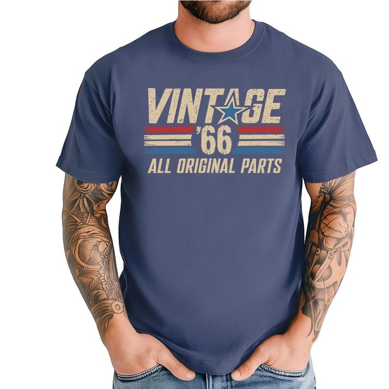 Puede incluir: Camiseta azul marino con el texto "VINTAGE '66 ALL ORIGINAL PARTS" en una fuente desgastada. El dise&ntilde;o incluye una estrella y rayas rojas y azules. La camiseta es de cuello redondo.