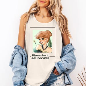 Puede incluir: Camiseta blanca de tirantes con una ilustraci&oacute;n verde y marr&oacute;n de una mujer con una corona y el texto "I Remember It All Too Well".