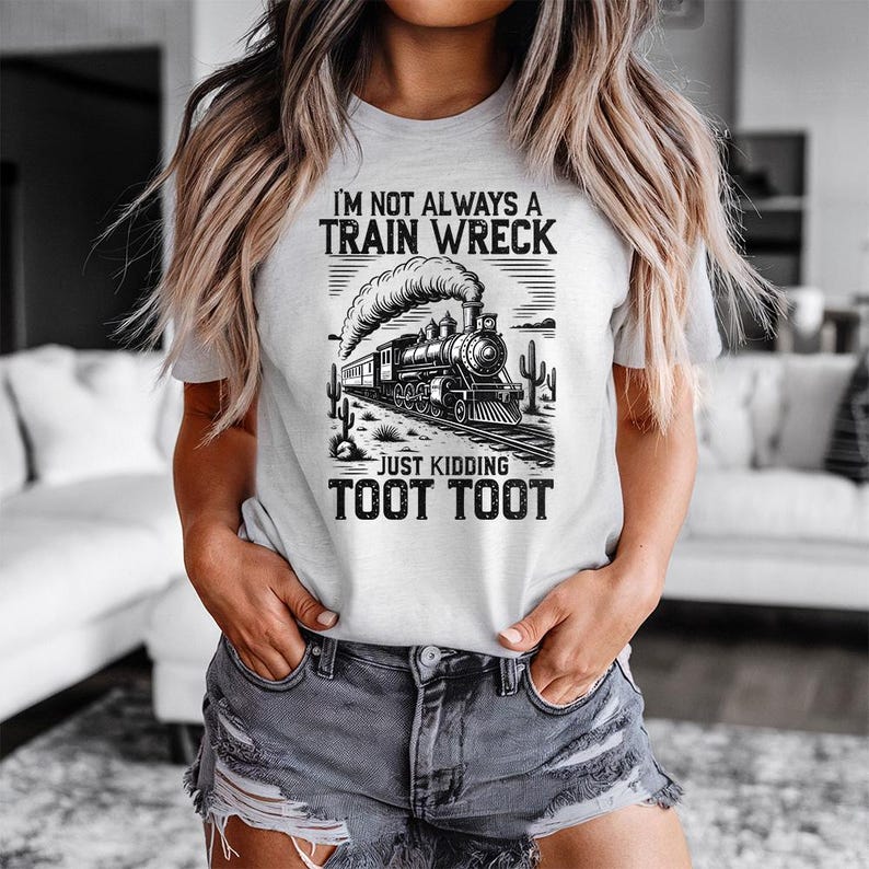 May include: A light gray t-shirt with a black and white graphic of a train and the text "I'M NOT ALWAYS A TRAIN WRECK JUST KIDDING TOOT TOOT". The design includes a train, cacti, and a desert landscape.