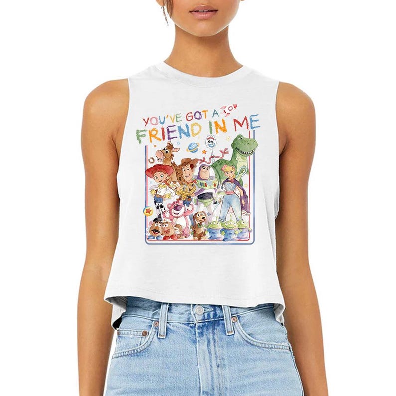 Puede incluir: Top corto sin mangas blanco con un gr&aacute;fico colorido de personajes de la pel&iacute;cula animada "Toy Story". El texto "YOU'VE GOT A FRIEND IN ME" est&aacute; impreso encima del gr&aacute;fico en una fuente l&uacute;dica. La parte superior est&aacute; hecha de un material suave.