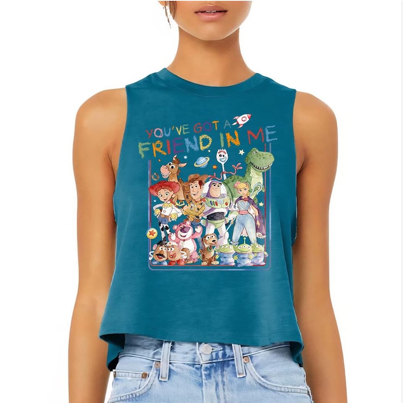 Puede incluir: Top corto sin mangas de color turquesa con un gr&aacute;fico colorido de personajes de Toy Story. El texto "YOU'VE GOT A FRIEND IN ME" est&aacute; impreso encima del gr&aacute;fico. La parte superior est&aacute; hecha de un material suave.