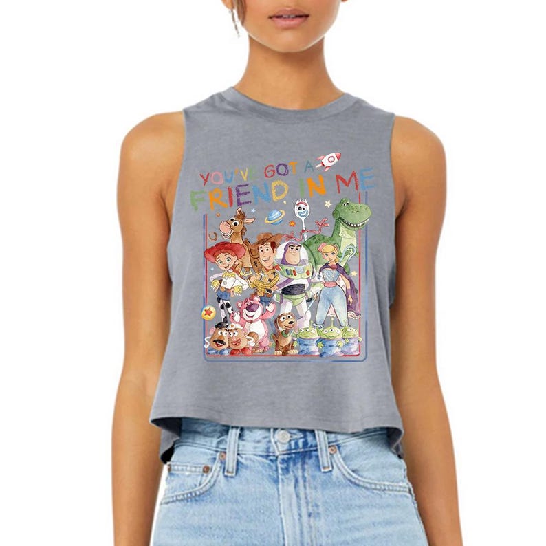 Puede incluir: Top corto sin mangas gris con un gr&aacute;fico colorido de personajes de la pel&iacute;cula "Toy Story". El texto "YOU'VE GOT A FRIEND IN ME" est&aacute; impreso encima de los personajes. El dise&ntilde;o incluye a Woody, Buzz Lightyear y otros personajes.