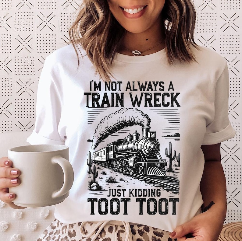 May include: White t-shirt with a black and white graphic of a vintage train, smoke, and desert cacti. The text reads "I'M NOT ALWAYS A TRAIN WRECK, JUST KIDDING, TOOT TOOT."