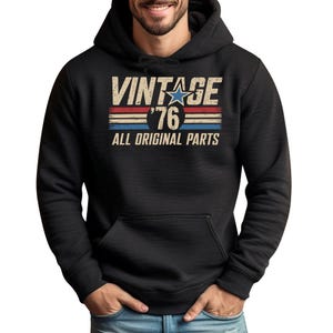 May include: Black hooded sweatshirt with the text "VINTAGE '76 ALL ORIGINAL PARTS" in a distressed, retro style. The design includes a star and horizontal stripes in red, white, and blue.