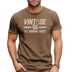 Puede incluir: Camiseta marr&oacute;n con el texto "VINTAGE '66 ALL ORIGINAL PARTS" en un estilo desgastado. El dise&ntilde;o incluye una estrella azul y rayas rojas y azules, creando un look retro. La camiseta es de manga corta.