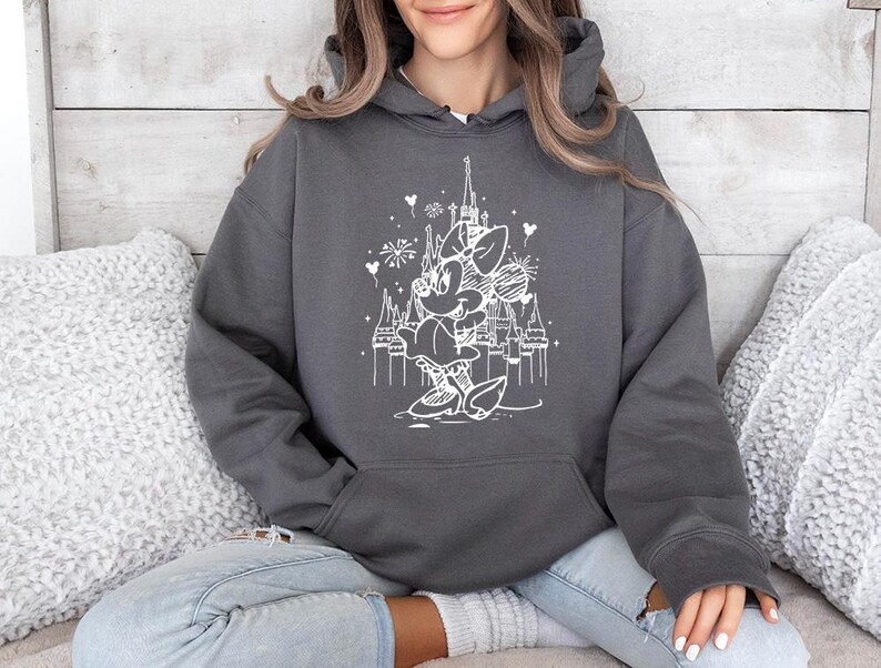 May include: A charcoal gray hooded sweatshirt featuring a white graphic of a cartoon character in front of a castle. The graphic includes fireworks and heart shapes. The sweatshirt has a front pocket and a drawstring hood.