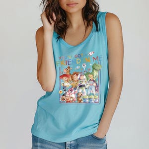 Pu&ograve; includere: Canotta azzurra con una grafica colorata dei personaggi del film "Toy Story". La grafica include Woody, Buzz Lightyear e altri personaggi, con la scritta "YOU'VE GOT A FRIEND IN ME."