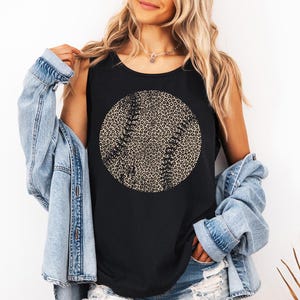 May include: Black vest top with a baseball design. The baseball graphic has a leopard print pattern and stitching details. The top is sleeveless and made of a soft material.