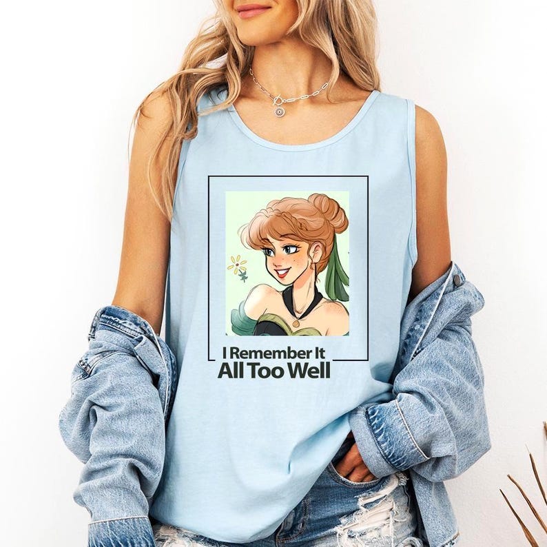 Puede incluir: Una camiseta sin mangas de color azul claro con un gr&aacute;fico de una mujer de dibujos animados con cabello casta&ntilde;o y un vestido verde. El texto "I Remember It All Too Well" est&aacute; impreso debajo del gr&aacute;fico.