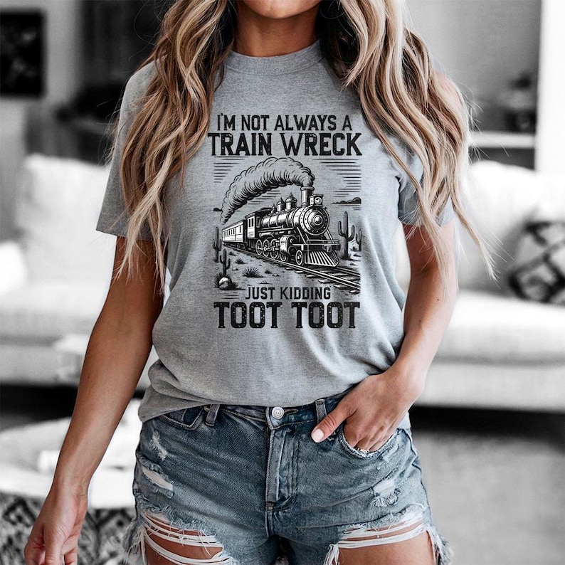 May include: A gray t-shirt with a black and white graphic of a steam train on tracks, with the text "I'M NOT ALWAYS A TRAIN WRECK JUST KIDDING TOOT TOOT". The shirt is short-sleeved.