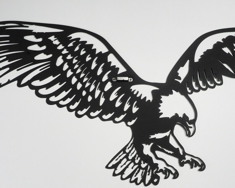 Op de afbeelding: Zwarte metalen wanddecoratie van een adelaar met uitgespreide vleugels. De adelaar is in vlucht en heeft een gedetailleerd ontwerp.