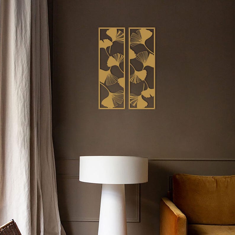 May include: Two rectangular wall panels with a gold leaf design. The panels are mounted on a dark brown wall. The leaves are stylized and arranged in a repeating pattern. The panels add a decorative touch to the room.