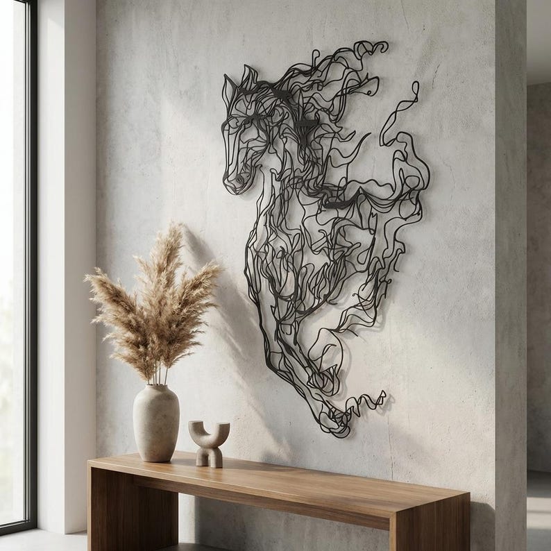 May include: Black metal wall art depicting a running horse. The sculpture is made of continuous lines, creating a flowing, dynamic form. The horse is mounted on a light gray wall, with a wooden console table and decorative vase in the foreground.