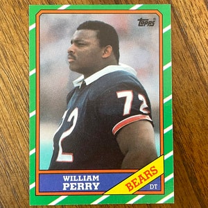 May include: A green, orange, and blue Topps trading card featuring a photo of William Perry, a football player for the Chicago Bears. The card has the text "Bears DT" and "William Perry" on it.