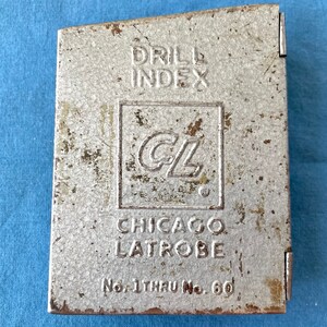 May include: A silver metal drill index box with the text "DRILL INDEX" and "CHICAGO LATROBE" printed on the front. The box is labeled "No. 1 THRU No. 60".