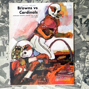 May include: A vintage NFL Illustrated program cover featuring a colorful illustration of two football players in action. The program is for the Browns vs Cardinals game, held on October 15, 1967, at Cleveland Municipal Stadium. The text "Crowd 77,513" is visible at the top of the program.