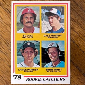 May include: A 1978 baseball card titled Rookie Catchers featuring four players: Bo Diaz of the Red Sox, Dale Murphy of the Braves, Lance Parrish of the Tigers, and Ernie Whitt of the Blue Jays. Each player is shown in a portrait wearing a team cap.
