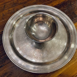 May include: A silver serving tray with a decorative design and a smaller silver bowl in the centre.