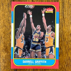 May include: A basketball trading card featuring Darrell Griffith, a basketball player for the Utah Jazz. The card is red, white, and blue with the text "FLEEER PREMIER" and "DARRELL GRIFFITH JAZZ GUARD".