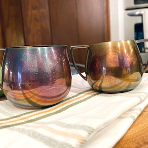 May include: Two silver-tone creamer and sugar sets with a pearlescent finish. The creamer and sugar are both round and have a handle.