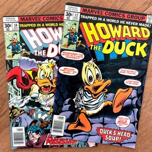 May include: Two vintage "Howard the Duck" comic books. The covers feature the cartoon duck in various action poses, with bold lettering and vibrant colours. Issue 14 shows Howard in a cape, while issue 12 has the text "Duck's Head Soup!"