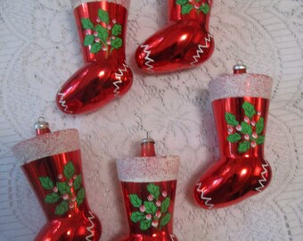 May include: Five red Christmas stocking ornaments with white glitter trim and holly berry designs. Each stocking has a silver metal loop for hanging. The stockings are approximately 4 inches tall.