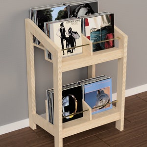 May include: A wooden record stand with two shelves, each holding multiple vinyl records. The stand has a brass rod on each shelf. The stand is light brown and has a simple design.
