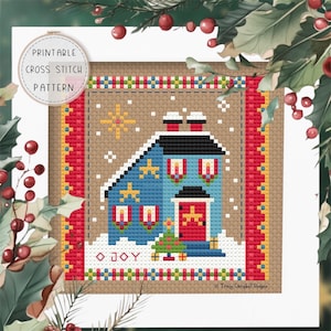 May include: A cross-stitch pattern depicting a blue house with a red door and festive decorations, a Christmas tree, and the word "JOY". The design is framed by a red and brown border, with the text "PRINTABLE CROSS STITCH PATTERN" in a circular frame.