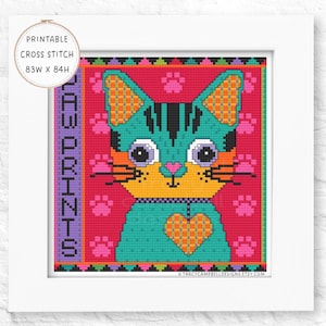 May include: A framed cross-stitch pattern with a vibrant cat design. The cat has teal fur with orange and black details, a yellow collar, and a heart-shaped chest. The background is pink with paw prints. The text "PAW PRINTS" is on the left side.