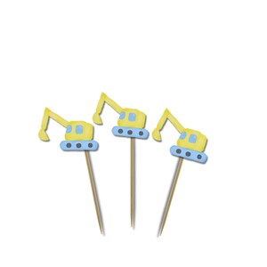 May include: Three yellow and blue excavator-shaped cupcake toppers on wooden sticks. The toppers have a blue base with three small dots and a yellow arm. The background is white.