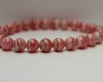 May include: A pink and white striped gemstone bracelet with round beads.