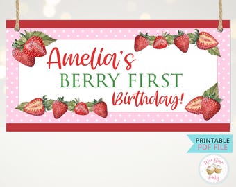 May include: A rectangular sign with a pink polka dot background and red borders. The sign features the text "Amelia's BERRY FIRST Birthday!" in red and green, with watercolor strawberries. Includes a "PRINTABLE PDF FILE" label.