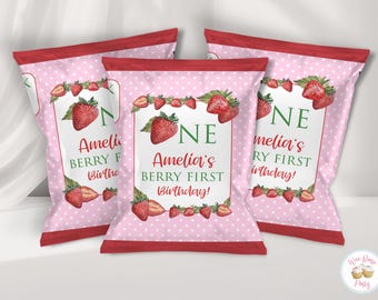 Puede incluir: Tres bolsas de snacks rectangulares con fondo rosa claro, lunares blancos y bordes rojos. El diseño central incluye fresas en acuarela, hojas verdes y el texto: ONE Amelia's BERRY FIRST Birthday!