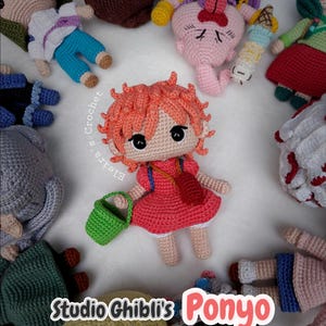 Op de afbeelding: Een verzameling handgemaakte gehaakte poppen, waaronder een centrale Ponyo-pop van Studio Ghibli, gekleed in een rode jurk en met een groene emmer. Andere poppen zijn eromheen gerangschikt. De tekst "Studio Ghibli's Ponyo" is zichtbaar.