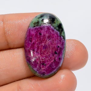 Peut inclure: Pierre précieuse ovale en cabochon avec un extérieur vert et noir et un intérieur rose. La pierre précieuse présente un motif tourbillonnant et est polie à un haut degré de brillance.