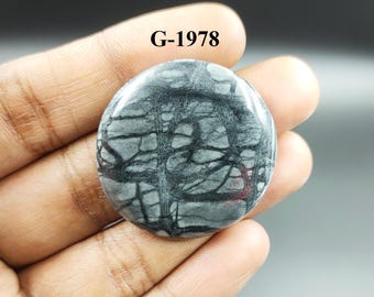 May include: A round, gray and black stone cabochon with a unique, swirling pattern. The stone is approximately 2 inches in diameter. G-1978