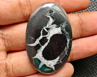 May include: A black and white oval cabochon gemstone with a swirling pattern. The gemstone is polished and has a glossy finish. The text "G-1211" is visible in the image.