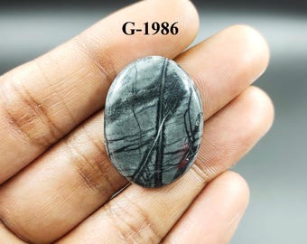 Könnte beinhalten: Ein grauer und schwarzer ovaler Cabochon-Edelstein mit einem einzigartigen Muster aus schwarzen Adern. Der Stein ist etwa 25 mm lang und 18 mm breit. G-1986