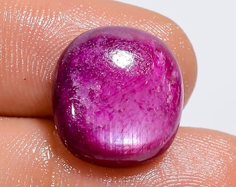 May include: A vibrant, oval-shaped ruby gemstone with a deep pink hue and a shimmering, iridescent finish.