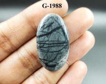 May include: Oval cabochon gemstone with a black and gray pattern. The stone is approximately 2 inches long and 1 inch wide. G-1988