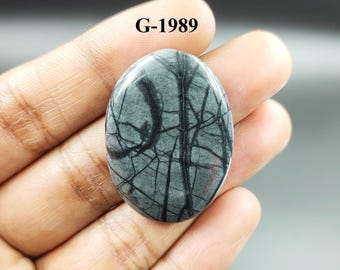 Könnte beinhalten: Ein grauer und schwarzer ovaler Cabochon-Edelstein mit einem dendritischen Muster. Der Stein ist mit "G-1989" gekennzeichnet.