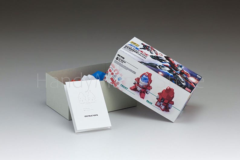 May include: A model kit box with a red and white design, open to reveal contents. The box features images of the assembled model and the text "RZ21". A white instruction booklet is in front of the box.