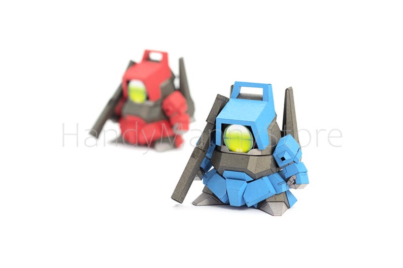 Pu&ograve; includere: Due figure simili a robot, una rossa e una blu, sono posizionate su uno sfondo bianco. Ogni figura ha un grande occhio rotondo giallo-verde e un accessorio a forma di pistola. Le figure sono fatte di forme geometriche angolari.