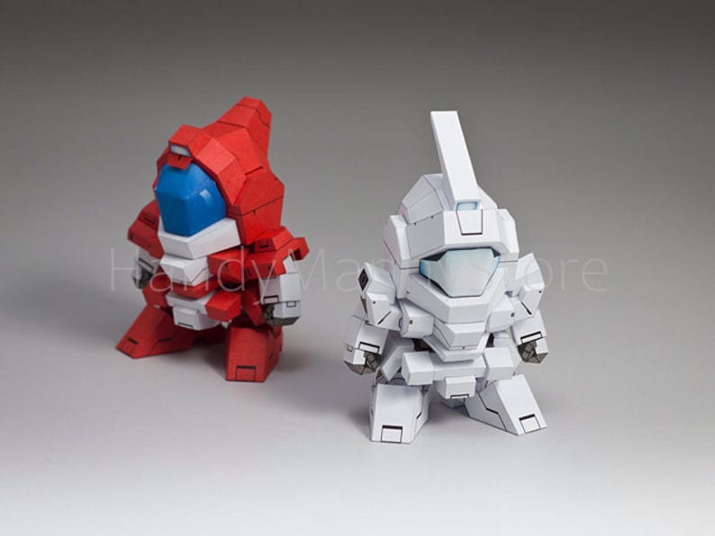 May include: Two stylized robot figures. One is red with blue and white accents, the other is white. Both have blocky designs and are posed in a squatting position. The robots appear to be toys or models.