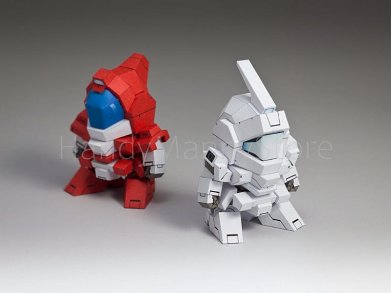 May include: Two stylized robot figures. One is red with white and blue accents, the other is white. Both have blocky designs and are posed in a crouching position. The background is a solid gray.