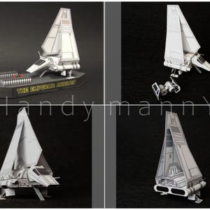 May include: A white and gray paper model of a spacecraft, with the text "THE EMPEROR'S ARRIVAL" on the base. The model is displayed in multiple views, showcasing its design and details. The spacecraft has a distinctive wing shape.