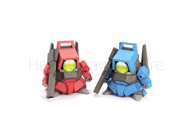 Pu&ograve; includere: Due figure simili a robot, una rossa e una blu, sono affiancate su uno sfondo bianco. Ognuna ha un grande occhio giallo brillante e un accessorio a forma di pistola. Le figure sono fatte di carta piegata angolare.
