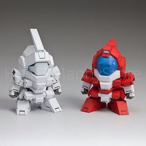 May include: Two small, stylized robot figures. One is white with a rectangular head and a raised fin. The other is red with a blue transparent dome for a head. Both have blocky, angular designs, suggesting a futuristic or sci-fi theme.